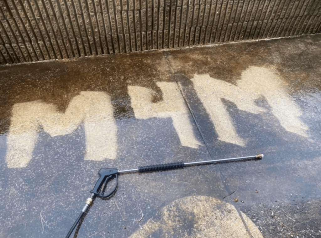 M4M logo cleaned into a concrete surface using a pressure washer